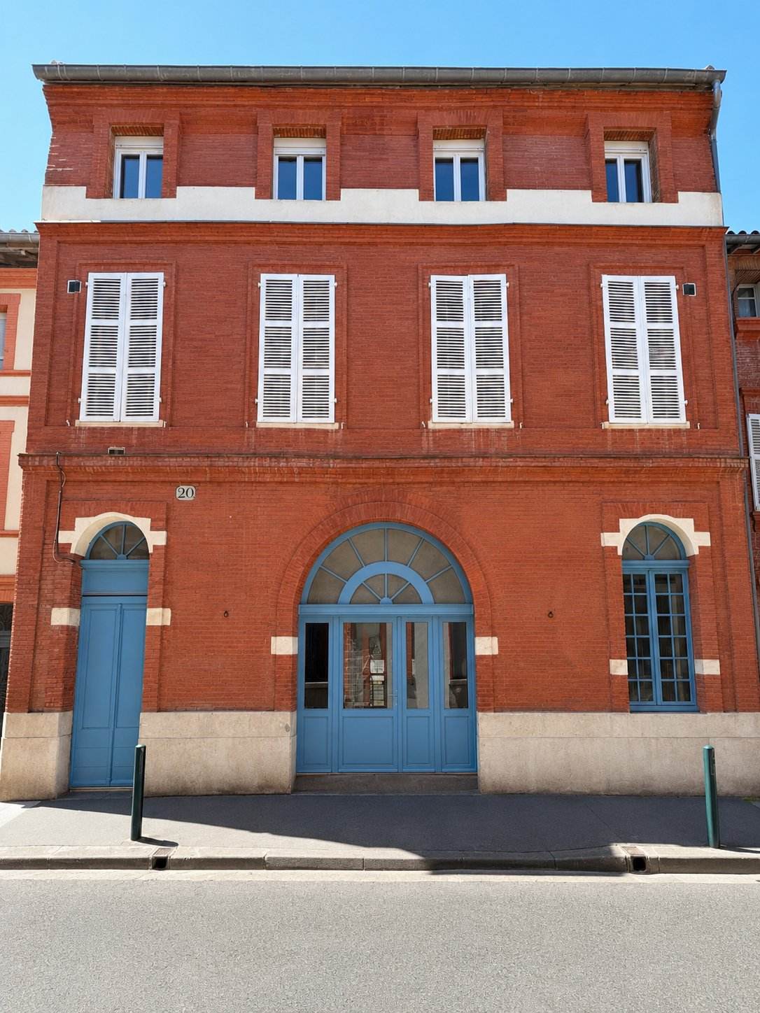 Façade en brique rouge du 20 rue Alfred Duméril, portes bleues en plein cintre